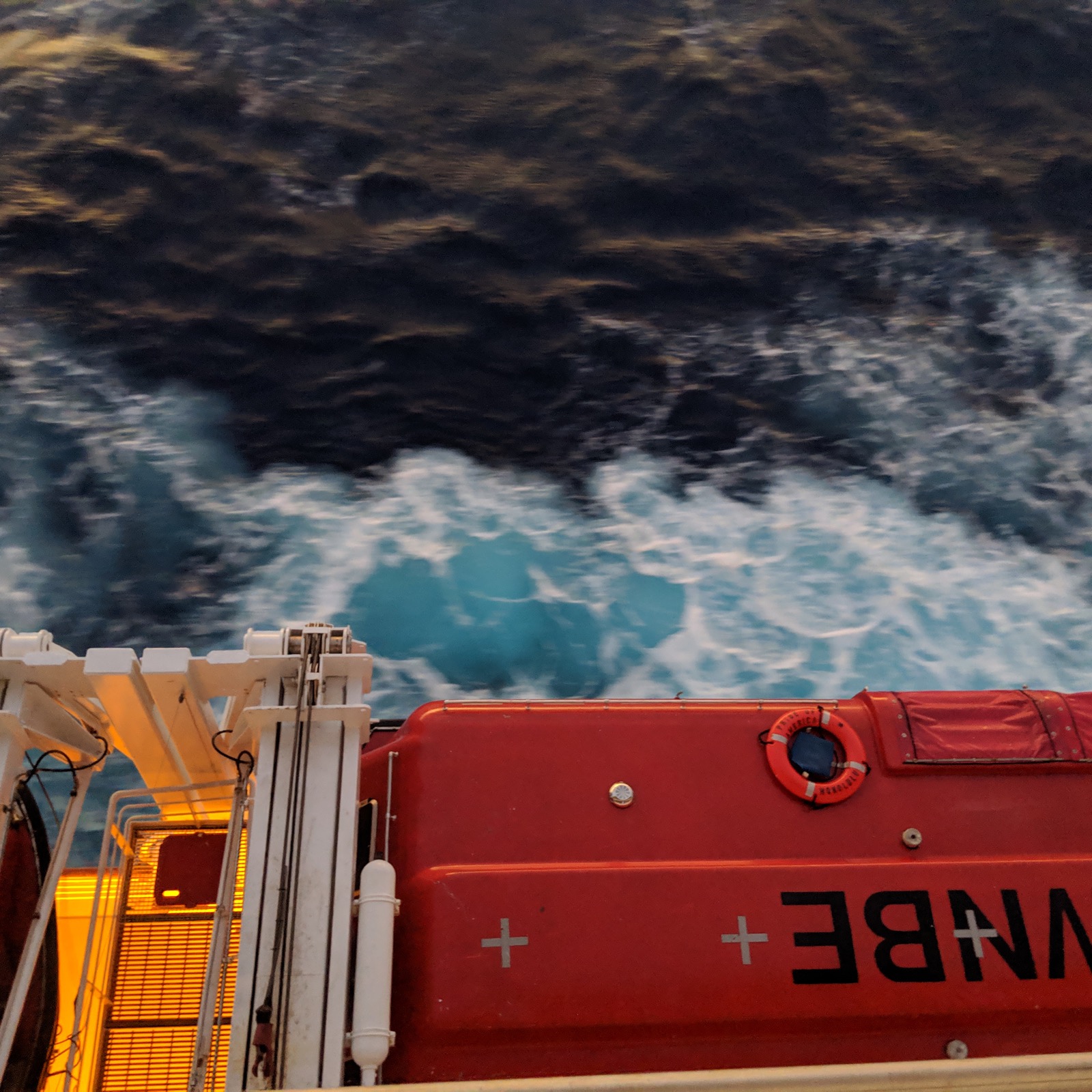 Dark churning water and the hull of a boat, seen from above.